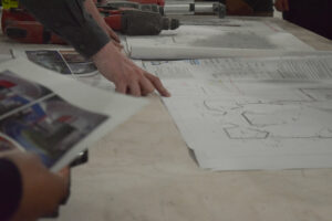 A person pointing at blueprints.