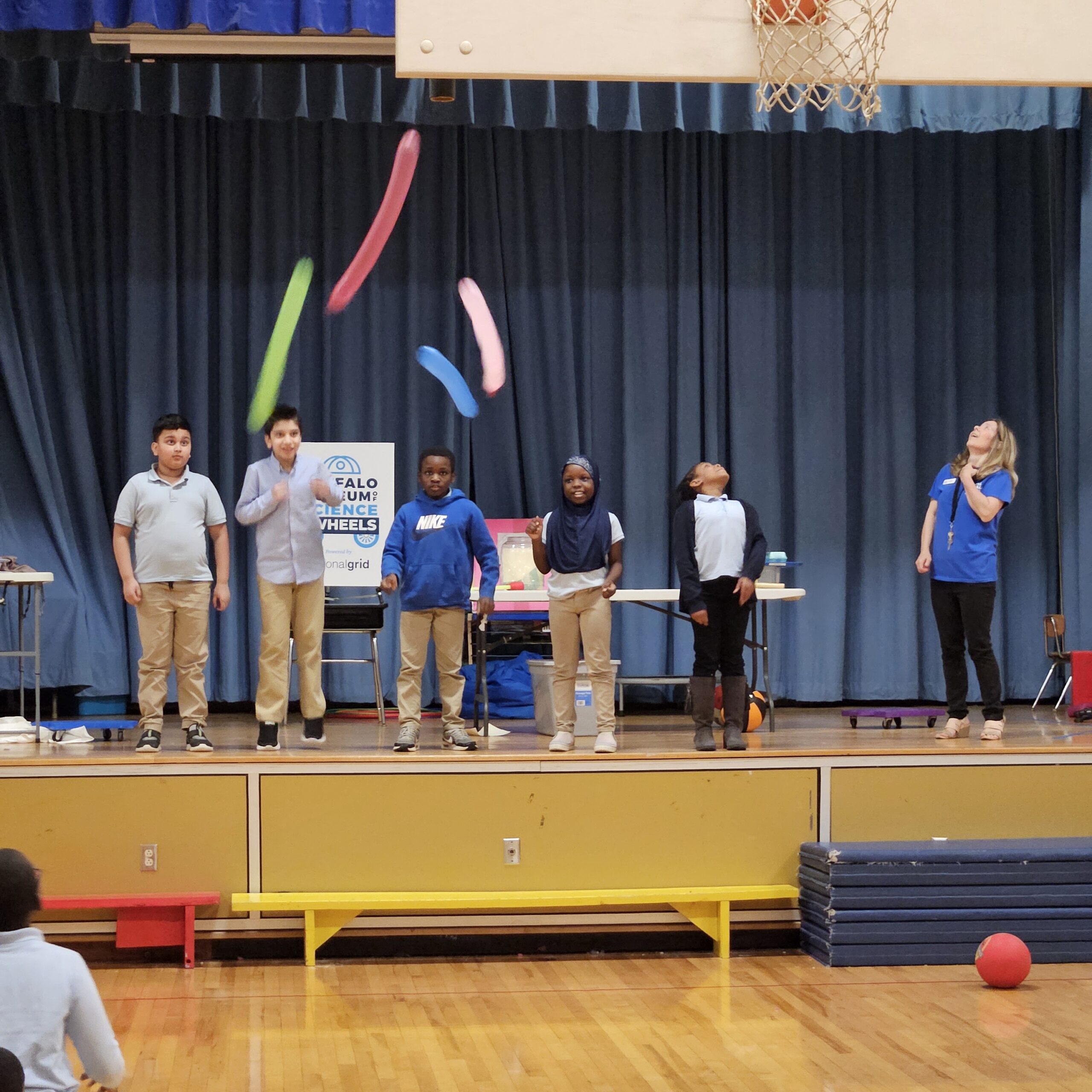 Kids standing on a stage with balloons.
